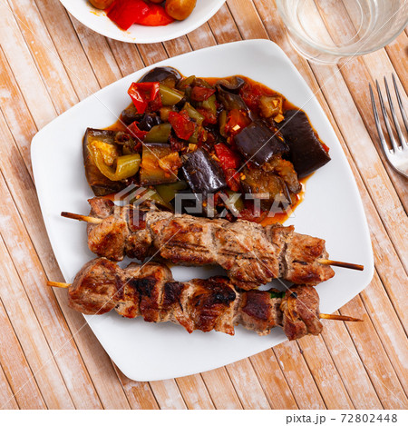 Grilled pork meat shashlik with sauteed vegetables Grilled pork meat shashlik with sauteed vegetables 72802448