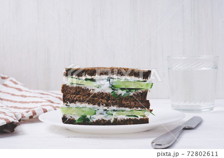 sandwich with black bread, cucumber and cream cheese on a plate on white background. vegetarian food concept sandwich with black bread, cucumber and cream cheese on a plate on white background. vegetarian food concept 72802611