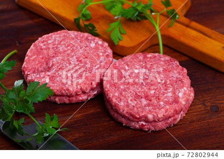 Raw meat cutlets with parsley on wooden board Raw meat cutlets with parsley on wooden board 72802944