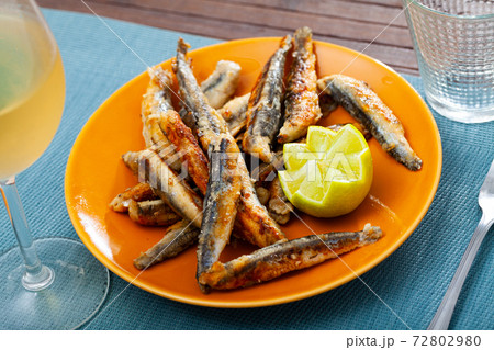 Fried anchovies served with slice of lemon 72802980