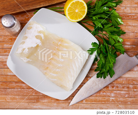 Uncooked rose eel fillet fish with parsley and garlic on table 72803510