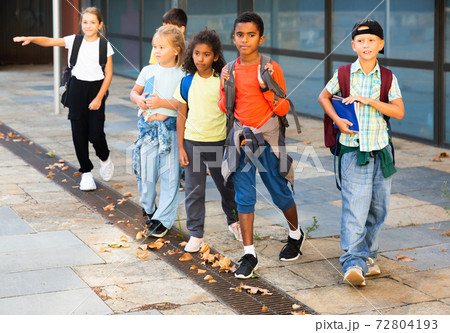 Smiling tweenagers walking outside school building on autumn day 72804193