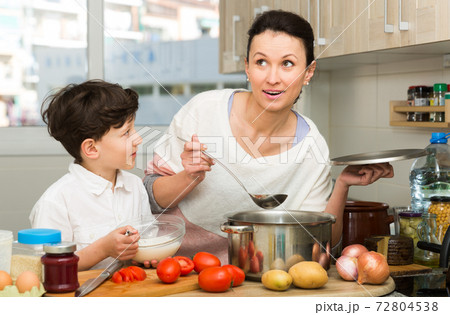 Smiling boy with mother preparing dinner 72804538