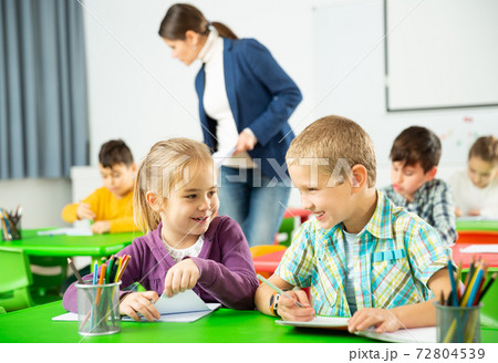Portrait of schoolchildren sitting in classroom and chatting during lesson 72804539