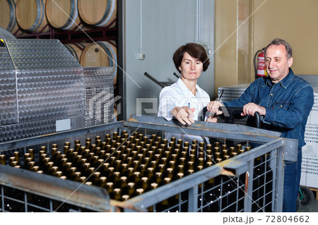Expert and wine maker inspect containers with bottles Expert and wine maker inspect containers with bottles 72804662