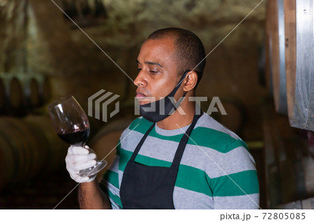 Worker of winery testing wine in glass 72805085