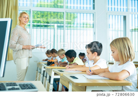 Focused preteen pupils studying in classroom with female teacher Focused preteen pupils studying in classroom with female teacher 72806630