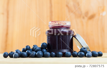 Tasty blueberry jam in jar and fresh berries on wooden surface Tasty blueberry jam in jar and fresh berries on wooden surface 72807575