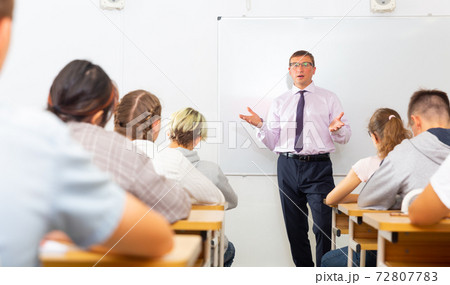 Male teacher lecturing to students at classroom Male teacher lecturing to students at classroom 72807783