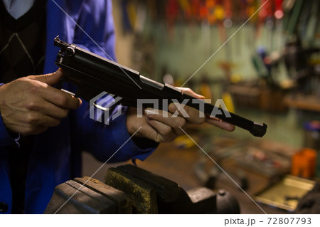 Gun repairman disassembling sporting handgun before preventive maintenance 72807793