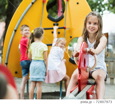 Smiling girl sitting on swing on children's playground 72807973