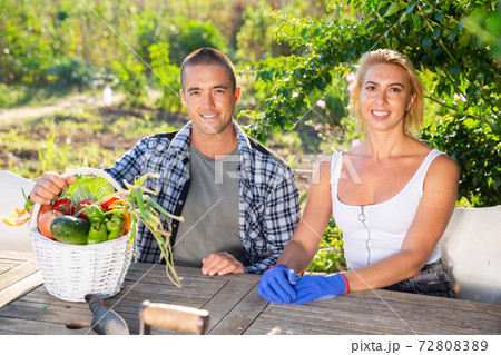 Smiling couple of gardeners with harvest of vegetables in backyard 72808389
