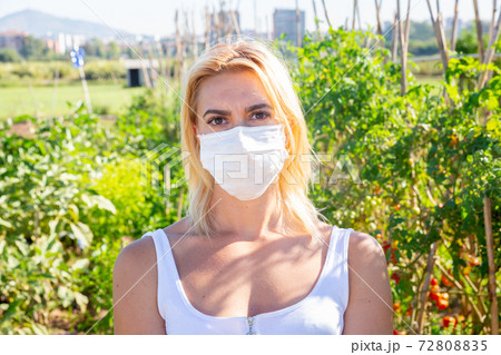Woman in protective mask posing in garden Woman in protective mask posing in garden 72808835