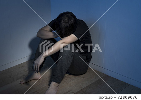 暗い部屋で床に座っている男性 暗い部屋で床に座っている男性 72809076
