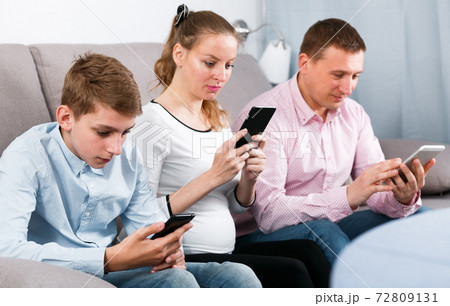 Parents and son using phones 72809131