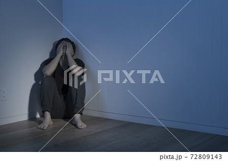 暗い部屋で床に座り込んだ男性 72809143