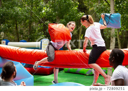 Women fighting by pillows on inflatable beam Women fighting by pillows on inflatable beam 72809251
