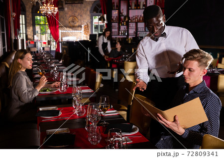 African American waiter helping client with menu 72809341