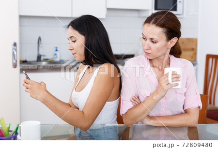 Mother looking into smartphone Mother looking into smartphone 72809480