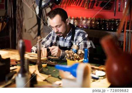 Worker processing leather for belt 72809682