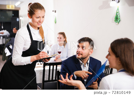 Woman waiter is taking order from clients in restaurante 72810149