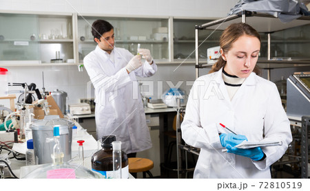 Female chemist writing results of experiments Female chemist writing results of experiments 72810519