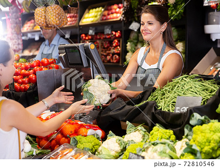 Girl seller offering cauliflower to customer 72810546