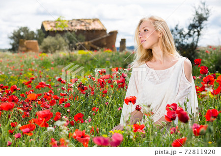 Beautiful young female in white dress in poppy field of wild flowers Beautiful young female in white dress in poppy field of wild flowers 72811920