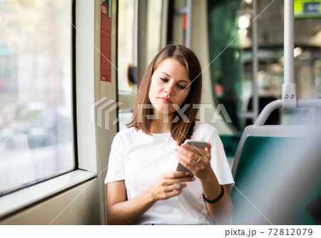 Woman using phone in modern tram Woman using phone in modern tram 72812079
