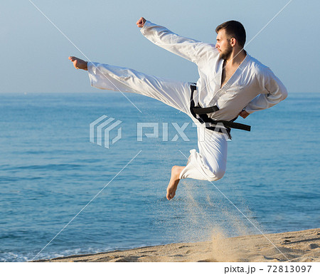 Man doing karate at ocean 72813097
