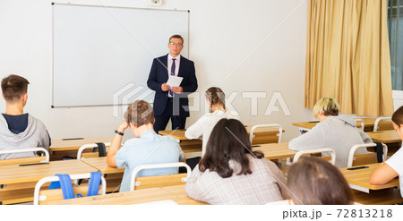 Teacher explaining studying material to teenagers during lesson 72813218