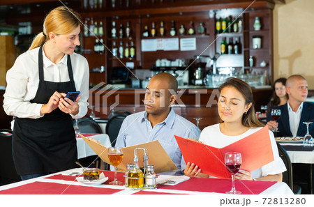 Positive couple making order with waitress in pizza restaurant Positive couple making order with waitress in pizza restaurant 72813280