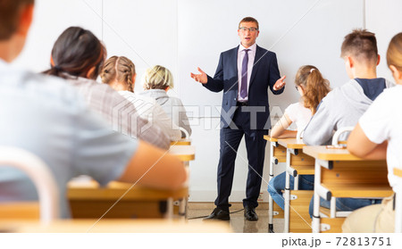 Teacher explaining studying material to teenagers during lesson 72813751