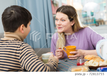 Portrait of young mother and son with tea talking at table 72813755