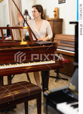 Pretty woman seller in piano music store 72814276