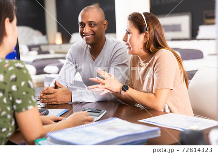 Young happy hispanic couple consulting with furniture saleswoman Young happy hispanic couple consulting with furniture saleswoman 72814323