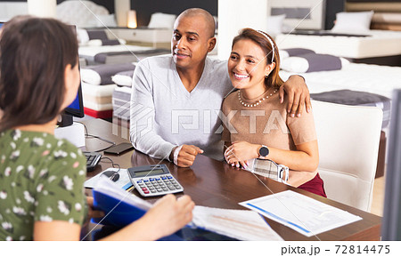 Couple talking to seller in furniture showroom Couple talking to seller in furniture showroom 72814475