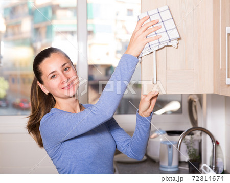 Smiling woman is cleaning surface on the kitchen at the home 72814674