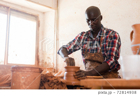 Craftsman woring with clay on potter wheel 72814938