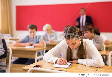 Teen girl sitting at desk in classroom 72815008