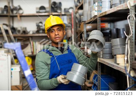 Salesman in overalls with plumbing fittings at hardware store warehouse Salesman in overalls with plumbing fittings at hardware store warehouse 72815123