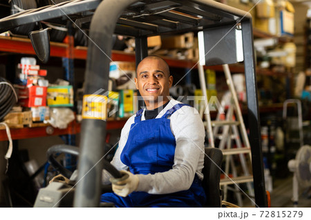 Cheerful worker of building materials warehouse driving forklift Cheerful worker of building materials warehouse driving forklift 72815279