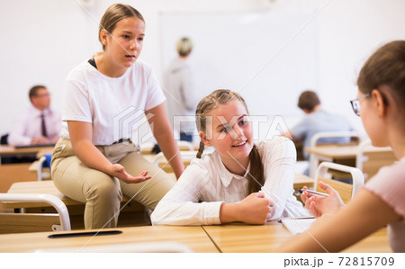 Teenage schoolgirls friendly talking during recess in classroom Teenage schoolgirls friendly talking during recess in classroom 72815709