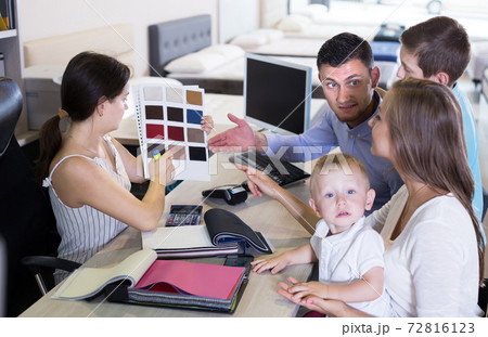 saleswoman in furniture store helping young family in choice of mattress material saleswoman in furniture store helping young family in choice of mattress material 72816123