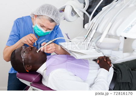 Dentist professional filling teeth for man patient sitting in medical chair Dentist professional filling teeth for man patient sitting in medical chair 72816170