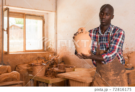 Craftsman examining handmade earthenware 72816175