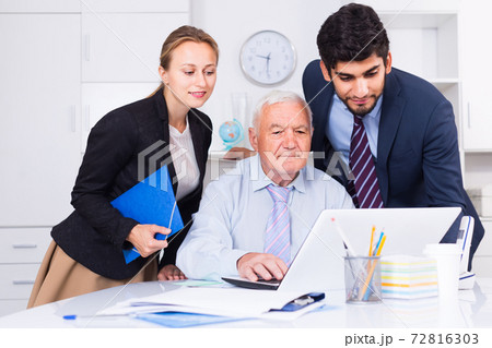 Employees are demonstrating reports on laptop to mature boss Employees are demonstrating reports on laptop to mature boss 72816303