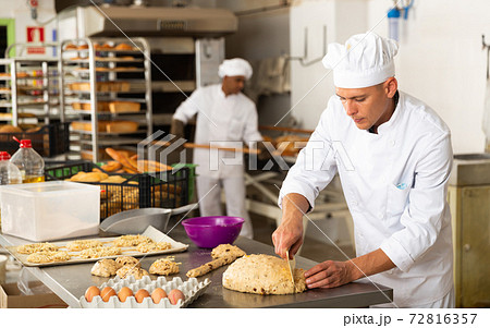Concentrated baker preparing sweet buns in bakery 72816357