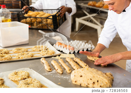 male baker in white uniform rolling out dough in kitchen male baker in white uniform rolling out dough in kitchen 72816503