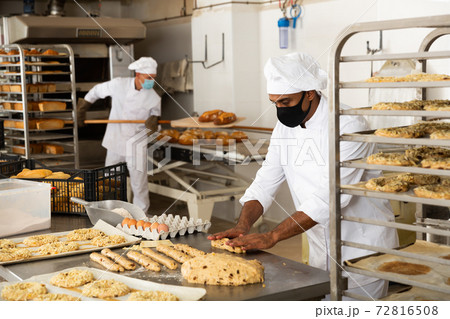 Male baker working with dough forming baguettes Male baker working with dough forming baguettes 72816508